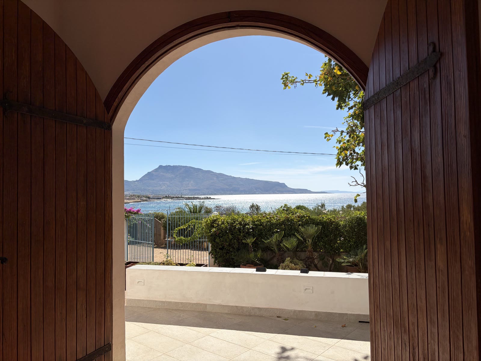 Wooden door opening onto the terrace with a view over the bay of Cornino