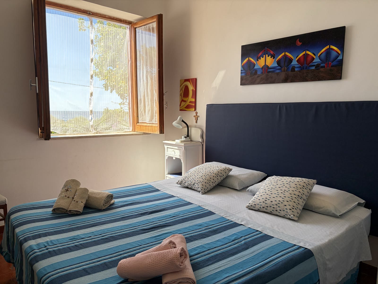 Bedroom with a blue striped bedspread and a sea-facing window