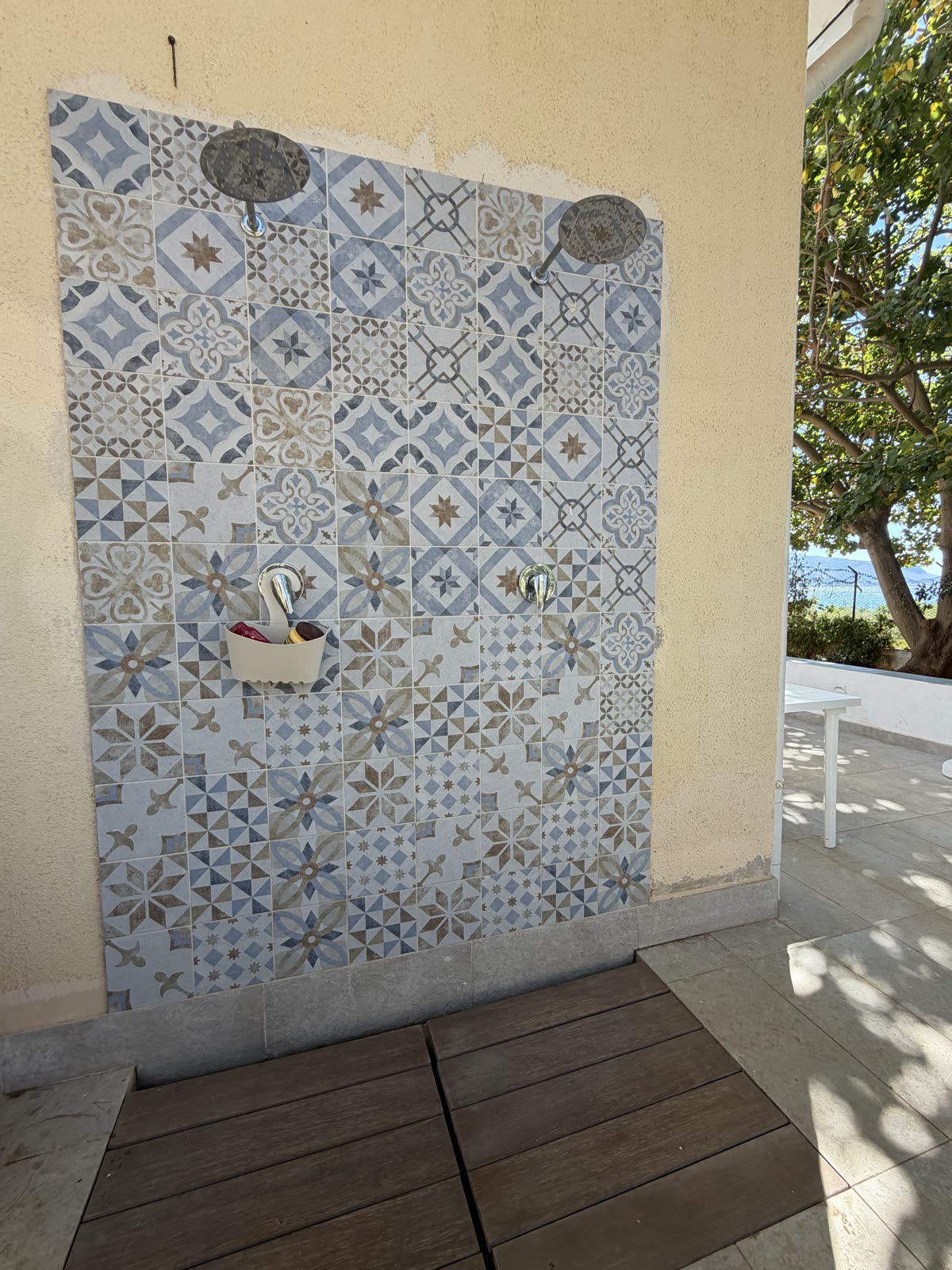 Outdoor shower with patterned cement tiles and wooden deck