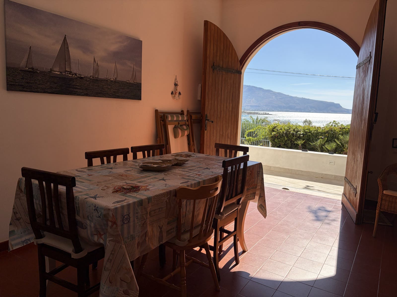 Dining table with the arched door open onto the sea view